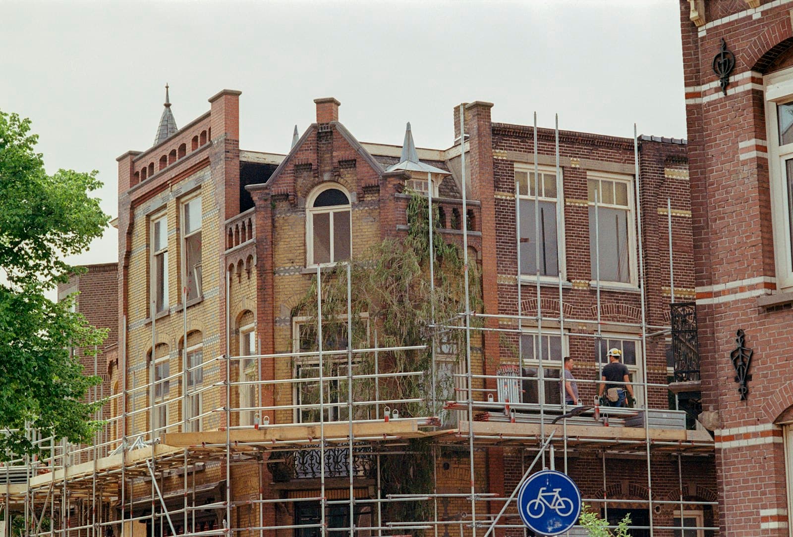 A European brick townhouse under renovation with scaffolding and two workers