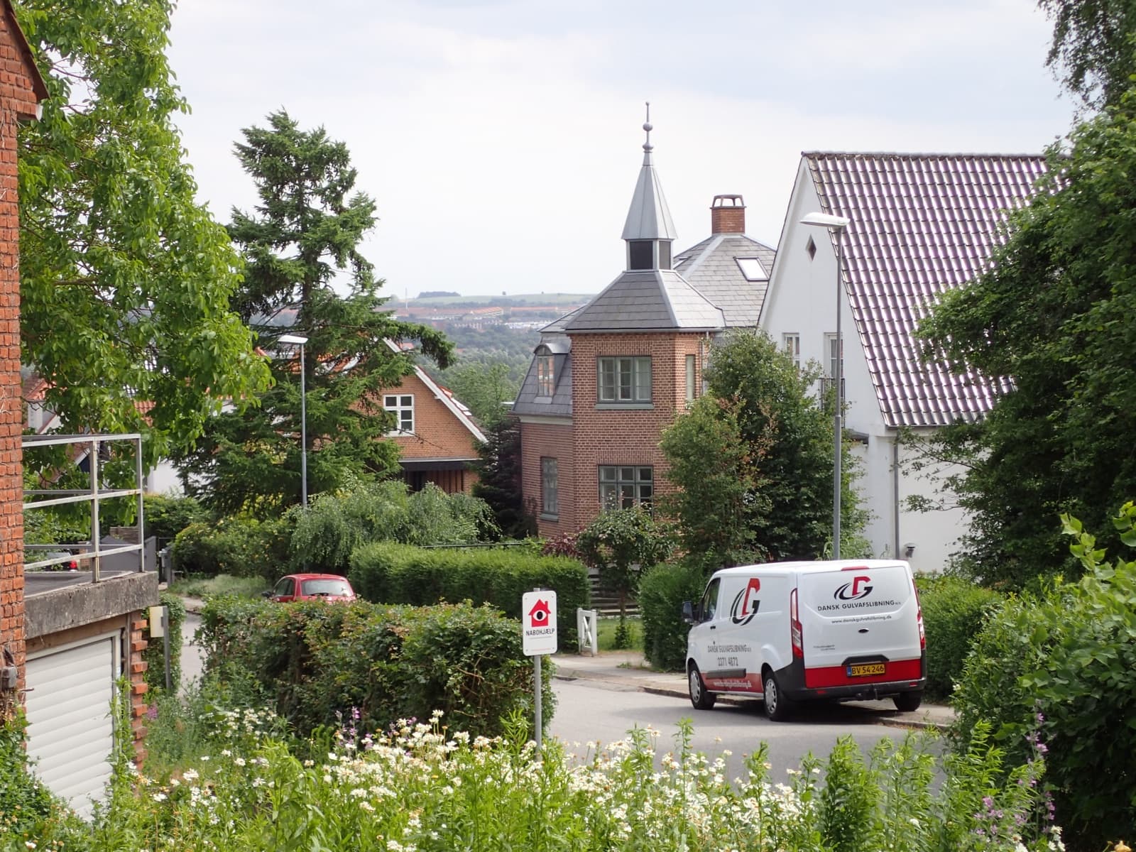 A leafy residential street of brick villas in Åbyhøj, a western suburb of Aarhus, in summer.