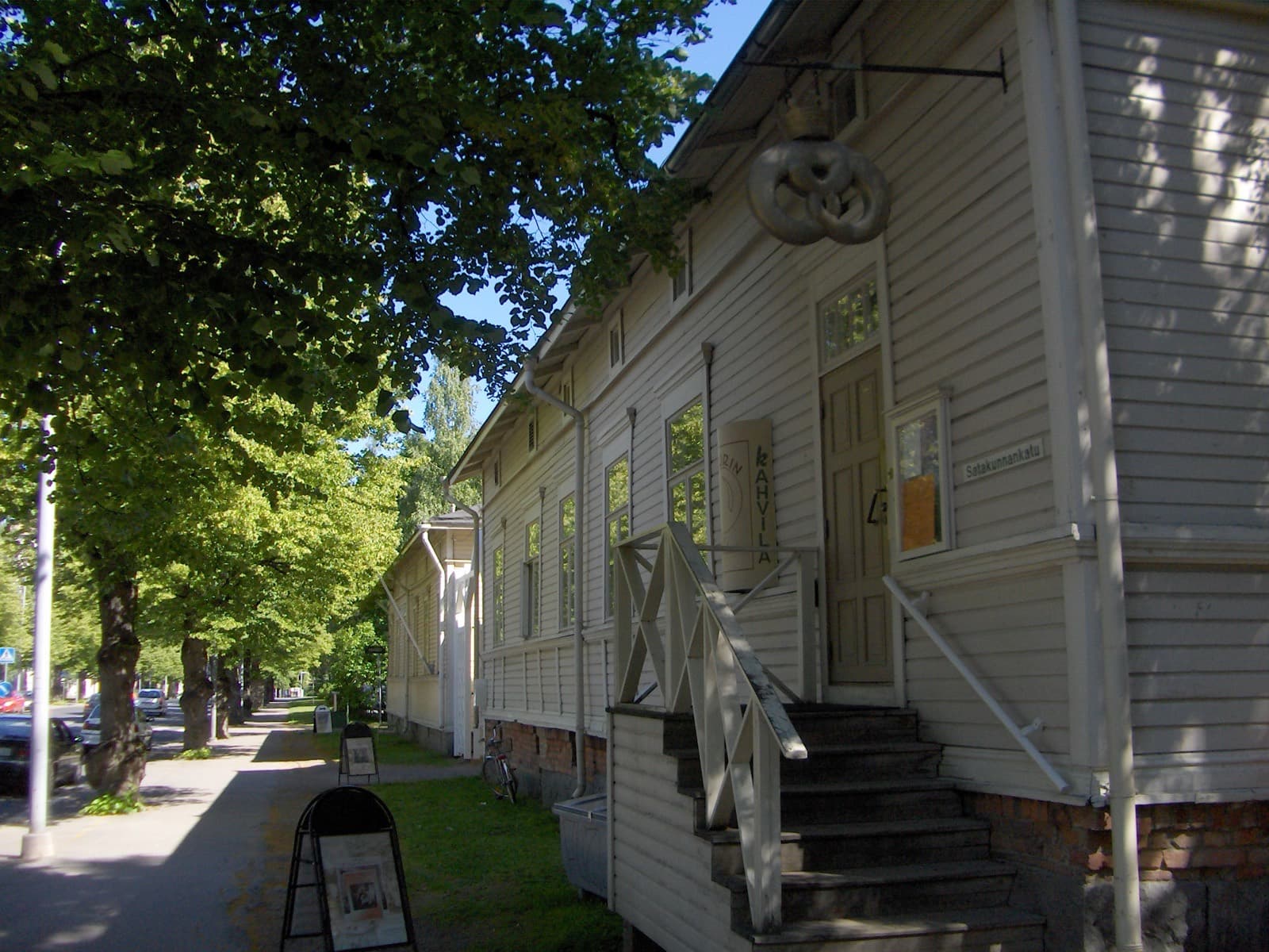 The wooden houses of the Amuri Museum of Workers' Housing along a lime-tree avenue in Amuri, Tampere, in summer sun.