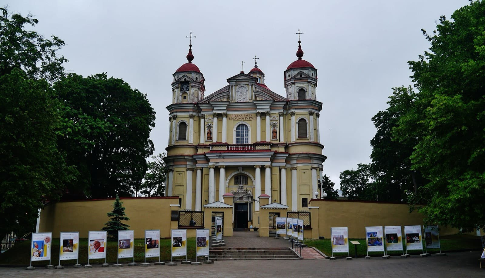 The yellow Baroque facade and twin red-domed towers of the Church of Saints Peter and Paul in Antakalnis.