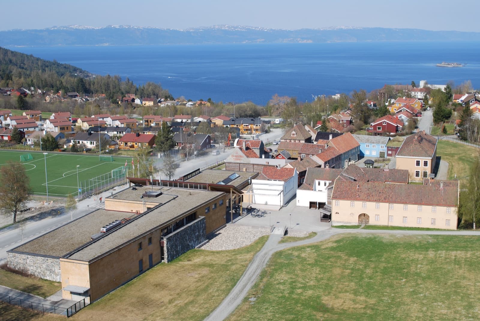 The Sverresborg open-air museum and the houses of the Byåsen hillside above the blue Trondheim Fjord, Byåsen, Trondheim, Norway.