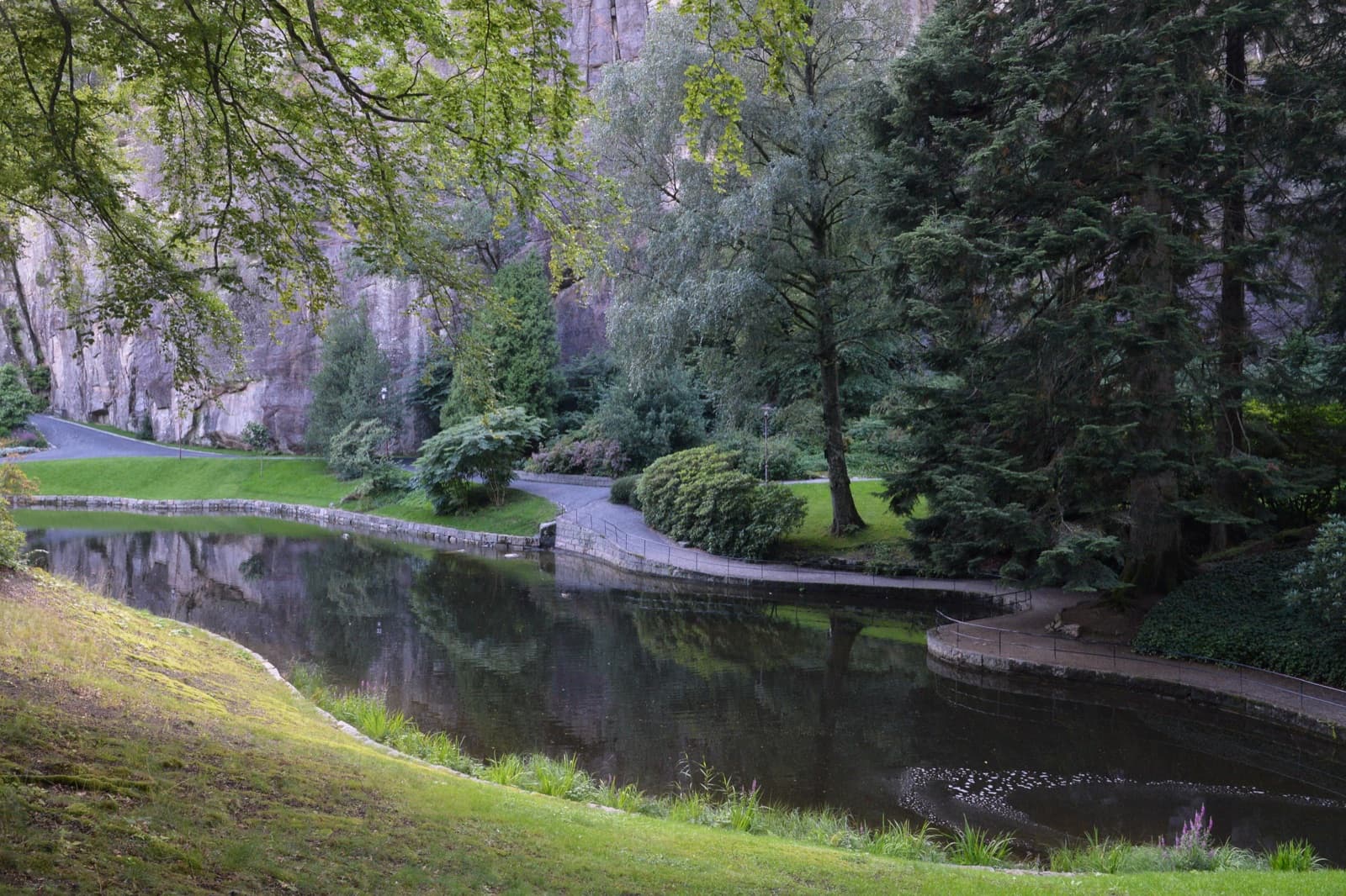 The pond, lawns and rock walls of Ravnedalen nature park on a summer day, Grim, Kristiansand, Norway.