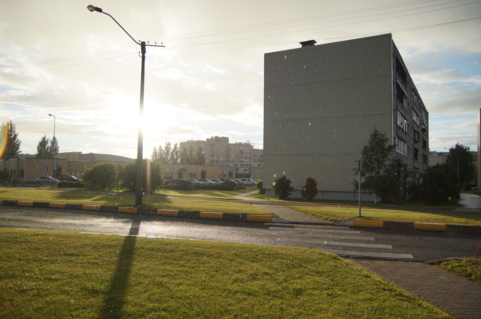 A quiet residential street of low apartment blocks with lawns and a lamp post in evening light in Kellamäe, Kuressaare.