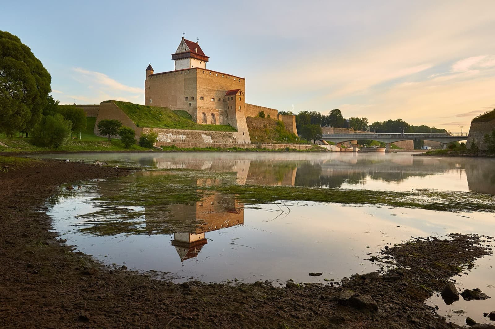 Narva Castle and its Tall Hermann tower reflected in the Narva river at sunrise