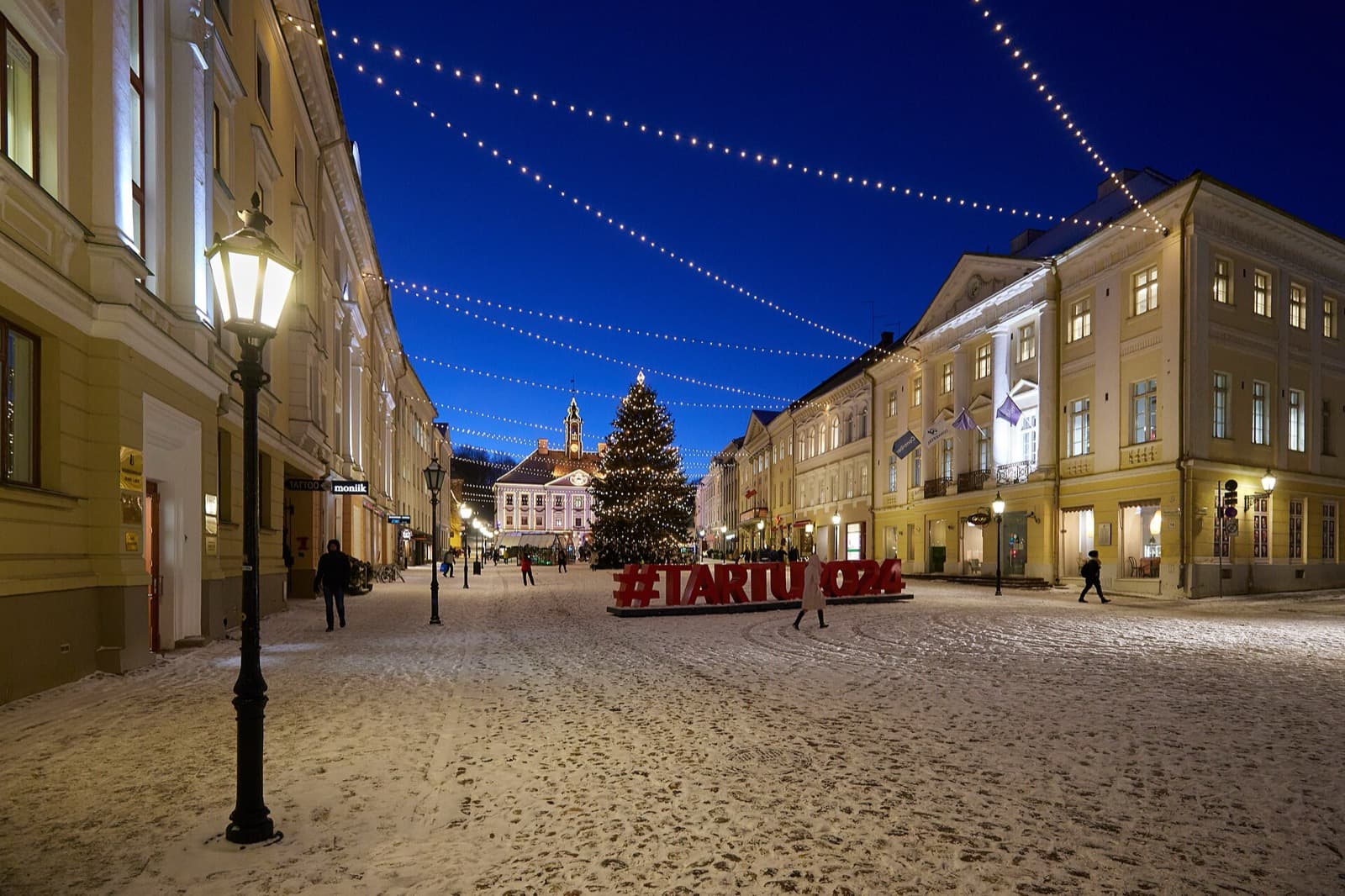 Raekoja plats, the town hall square in central Tartu, lit for winter with the pink town hall and a Christmas tree at the far end.