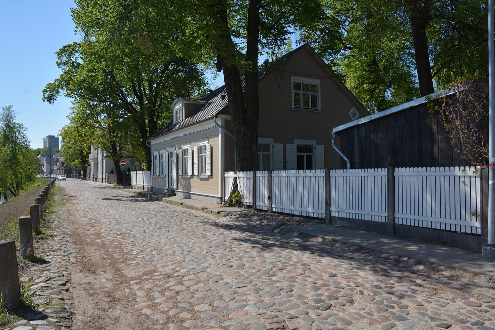 The cobbled Balasta dambis lined with restored wooden houses on Ķīpsala island beside the Daugava.