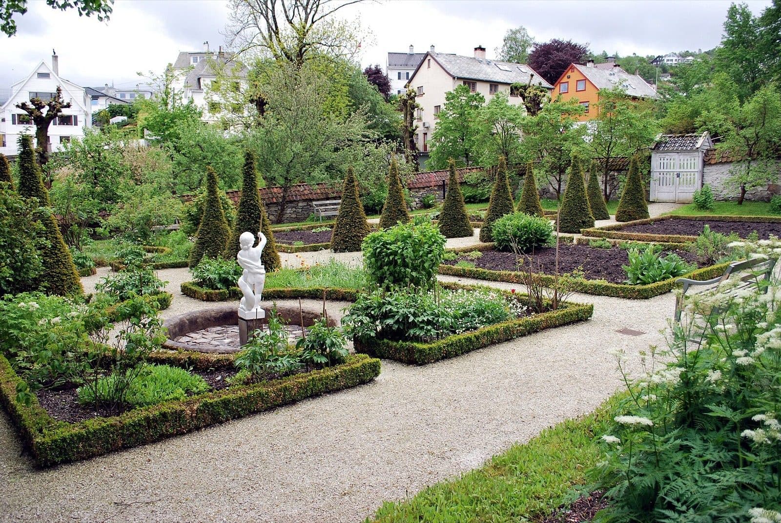 The restored baroque garden at Damsgård Manor in Laksevåg, Bergen, with clipped topiary and the houses of the district behind.