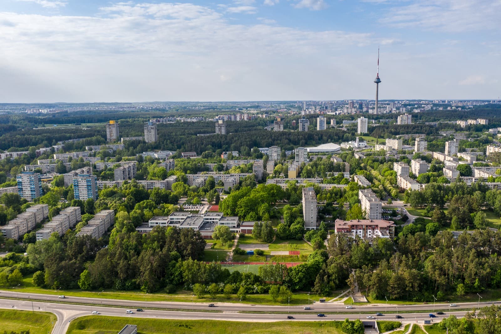 An aerial view of the forested modernist housing estate of Lazdynai with the Vilnius TV Tower rising beyond it.