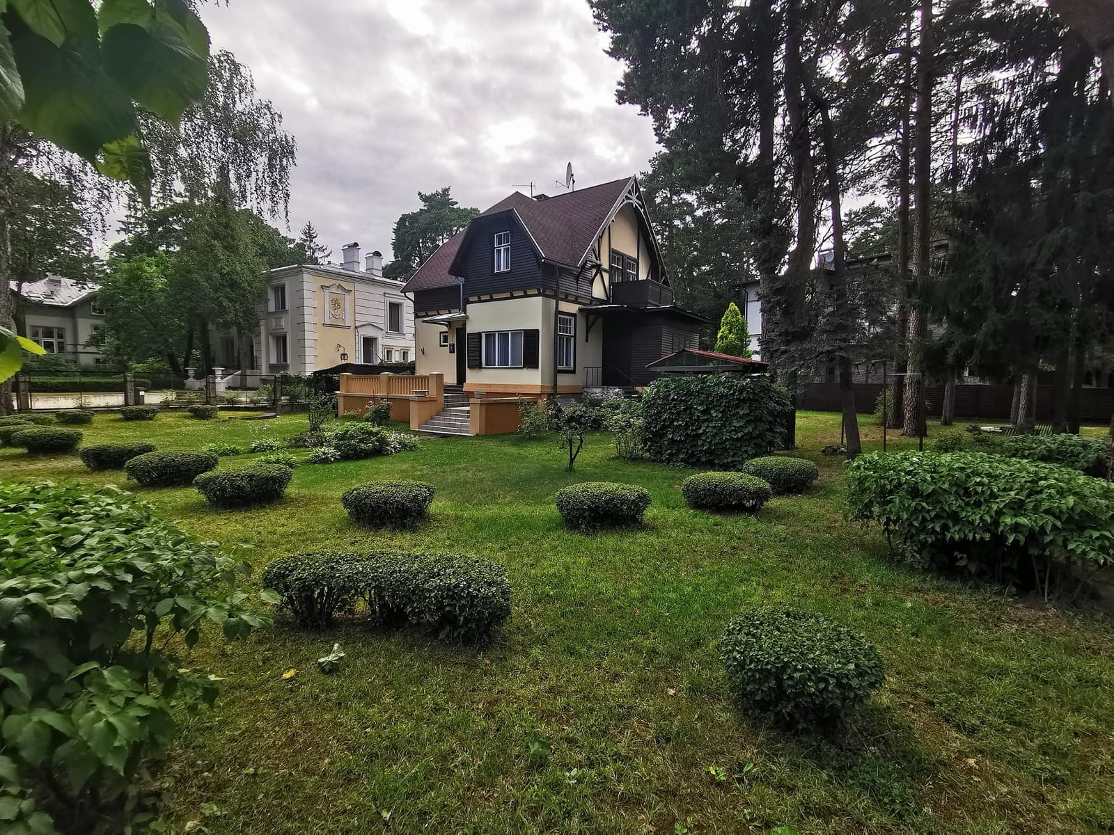 A garden-city villa and its clipped hedges among the pines in Mežaparks.