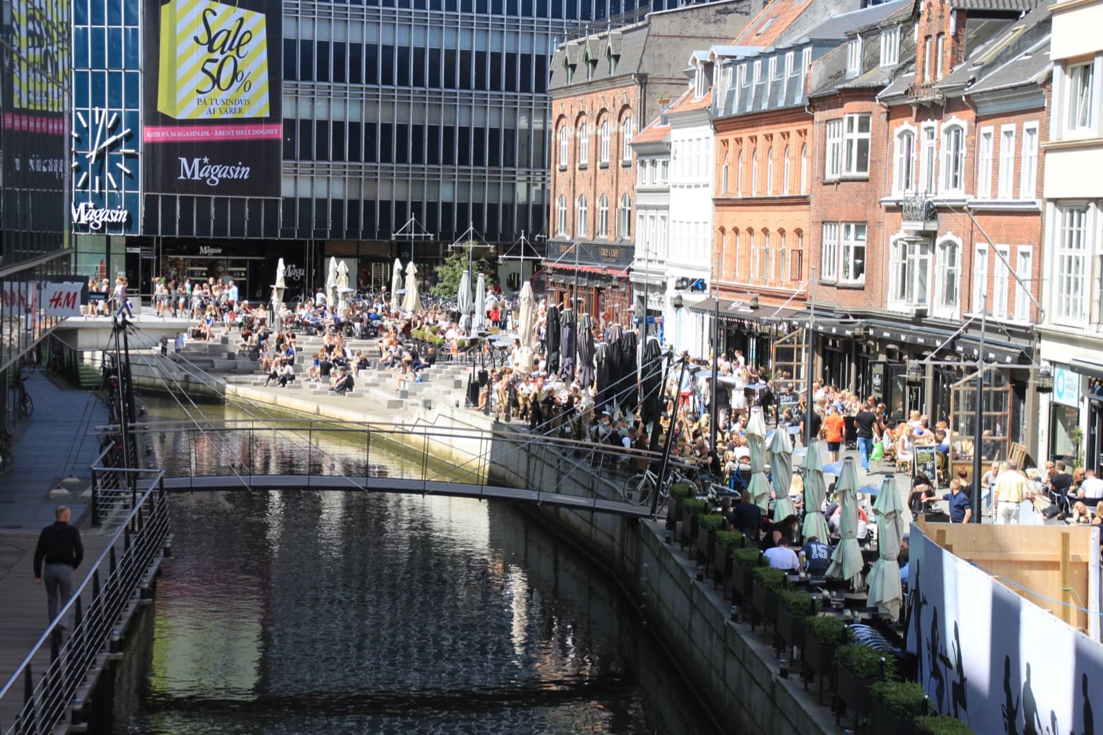 The Åboulevarden canal in the old town of Aarhus, lined with busy cafes on a sunny day.