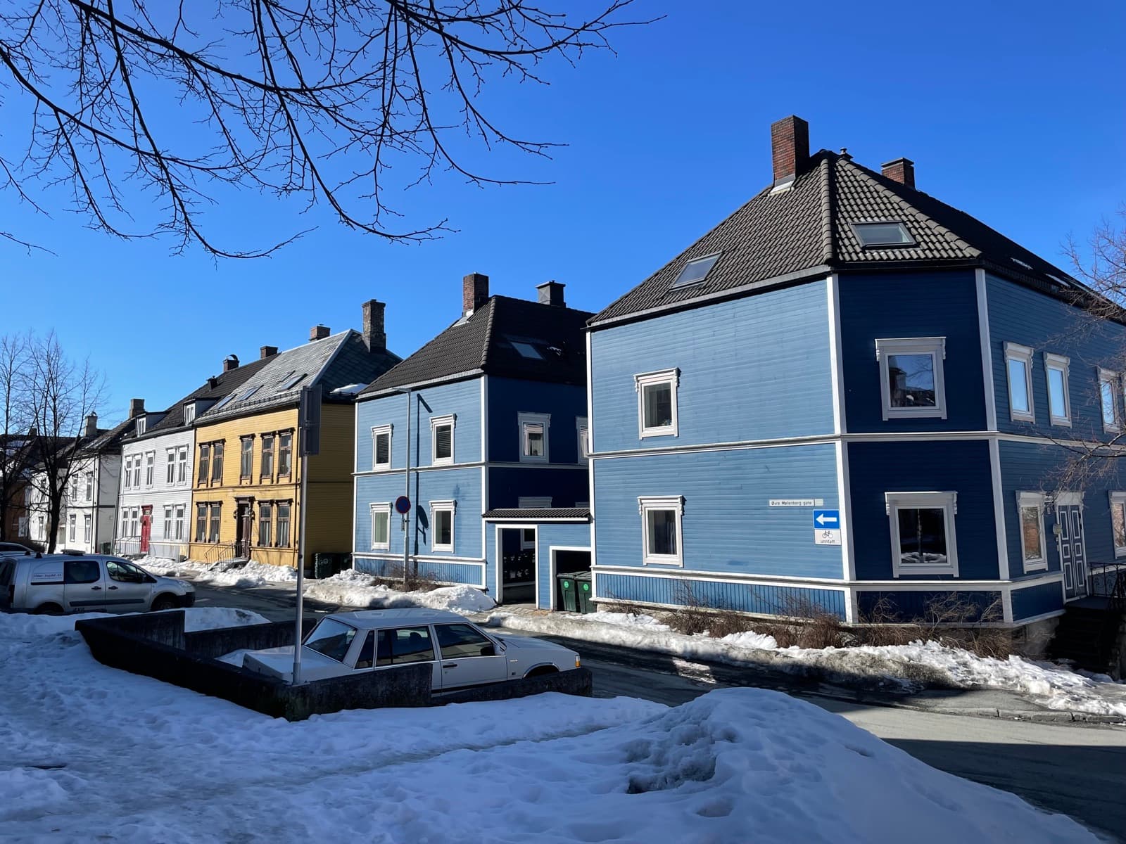 Painted wooden apartment houses in blue and yellow on the corner of Øvre Møllenberg gate under a clear winter sky, Møllenberg, Trondheim, Norway.