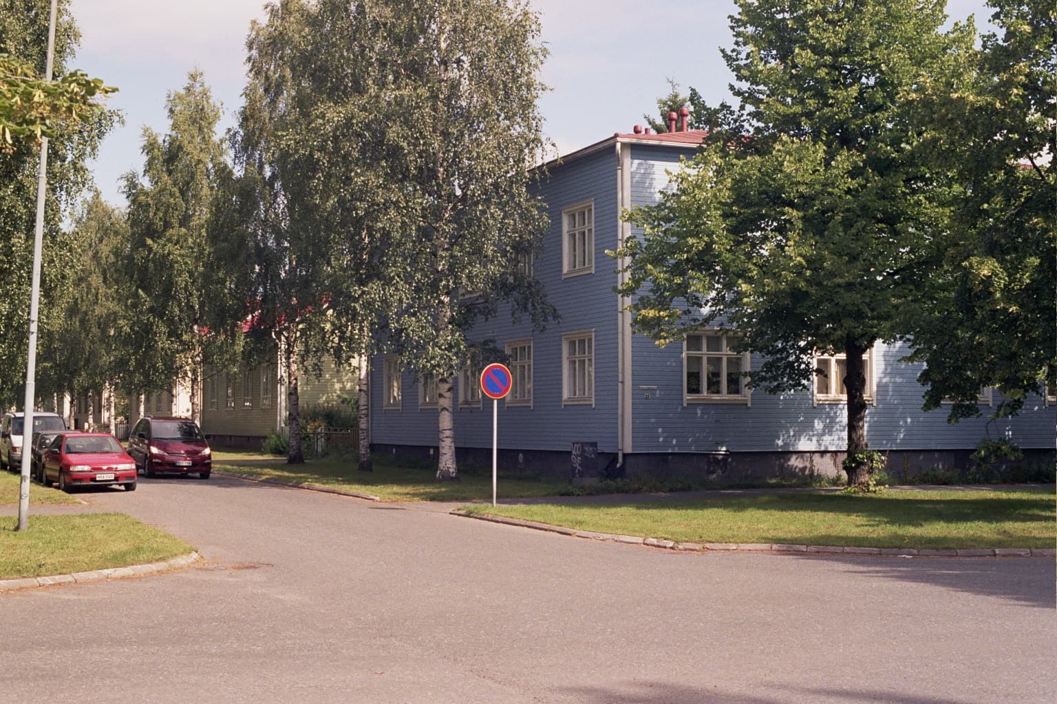 A blue wooden house among birches on a quiet street in Puu-Raksila, the old wooden quarter of Raksila in Oulu.