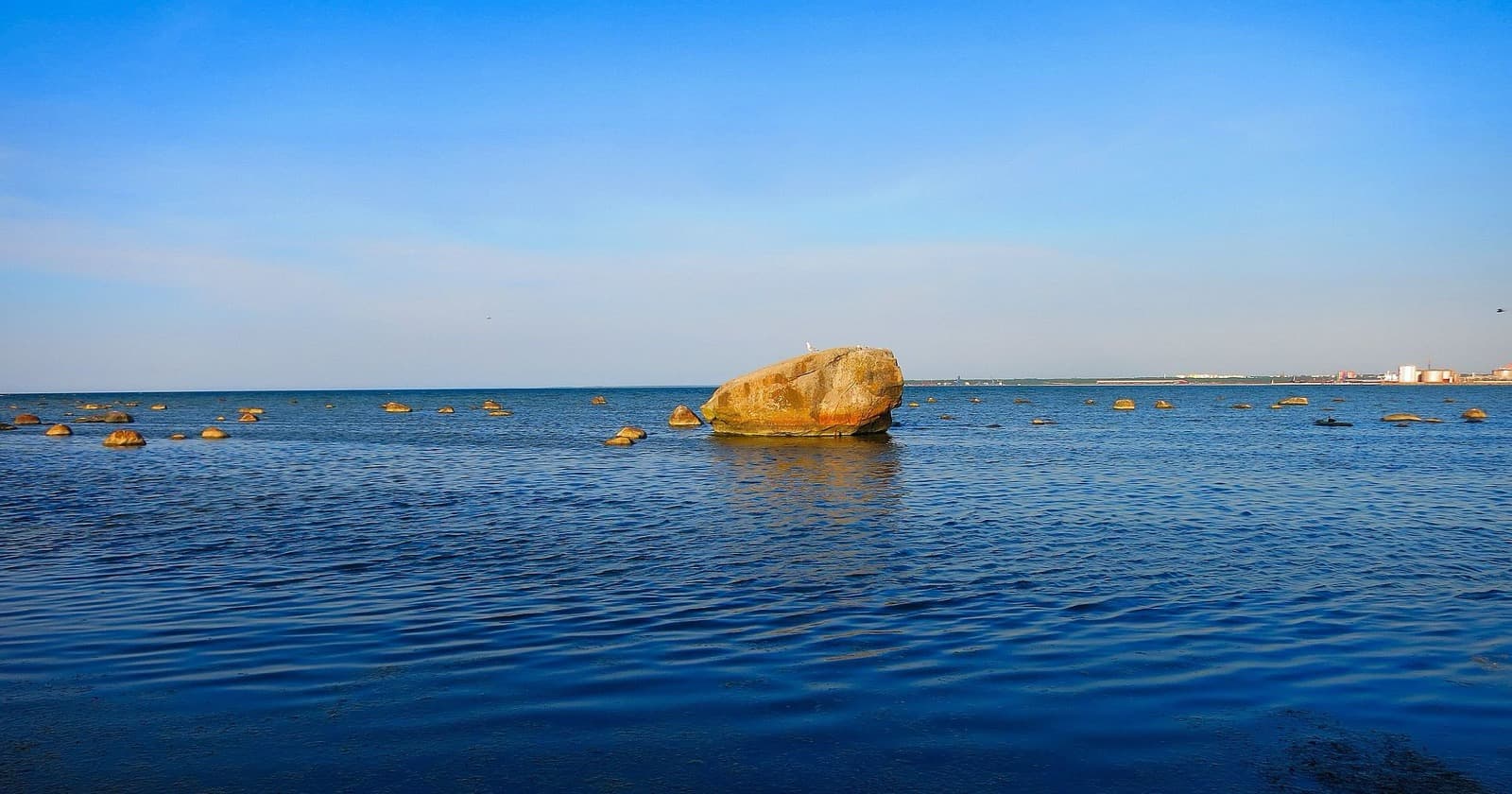 The Baltic shoreline at Randvere, with the Hallikivi boulder standing offshore among scattered rocks.