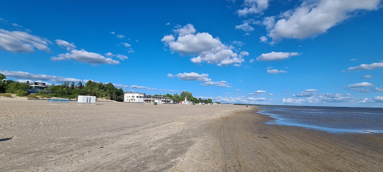 The wide sandy Pärnu beach in the Rannarajoon district, with the beach house and Baltic shore under a summer sky
