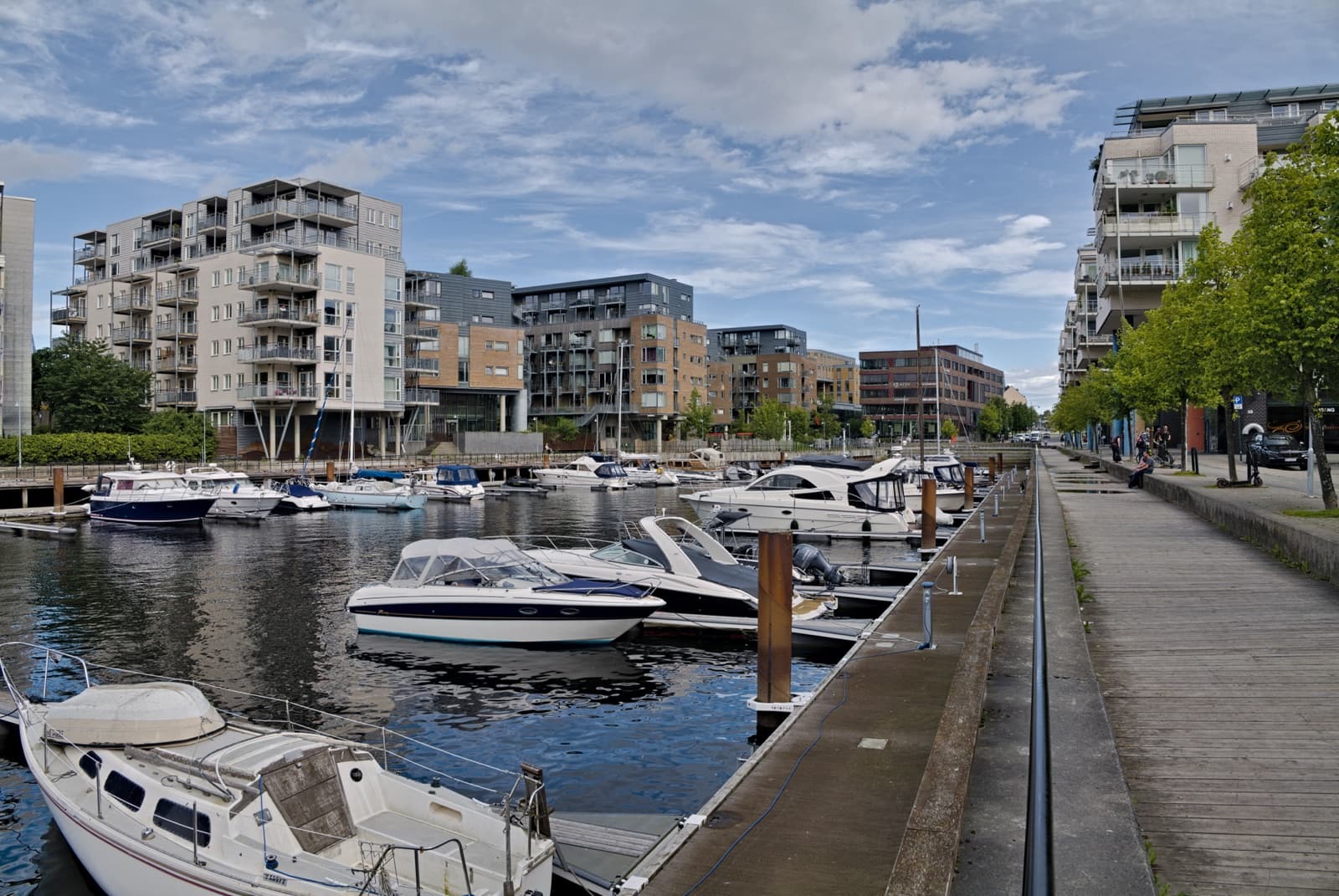 Boats moored in the old shipyard basin at Nedre Elvehavn, with the modern waterfront apartment blocks of Solsiden behind, Trondheim, Norway.