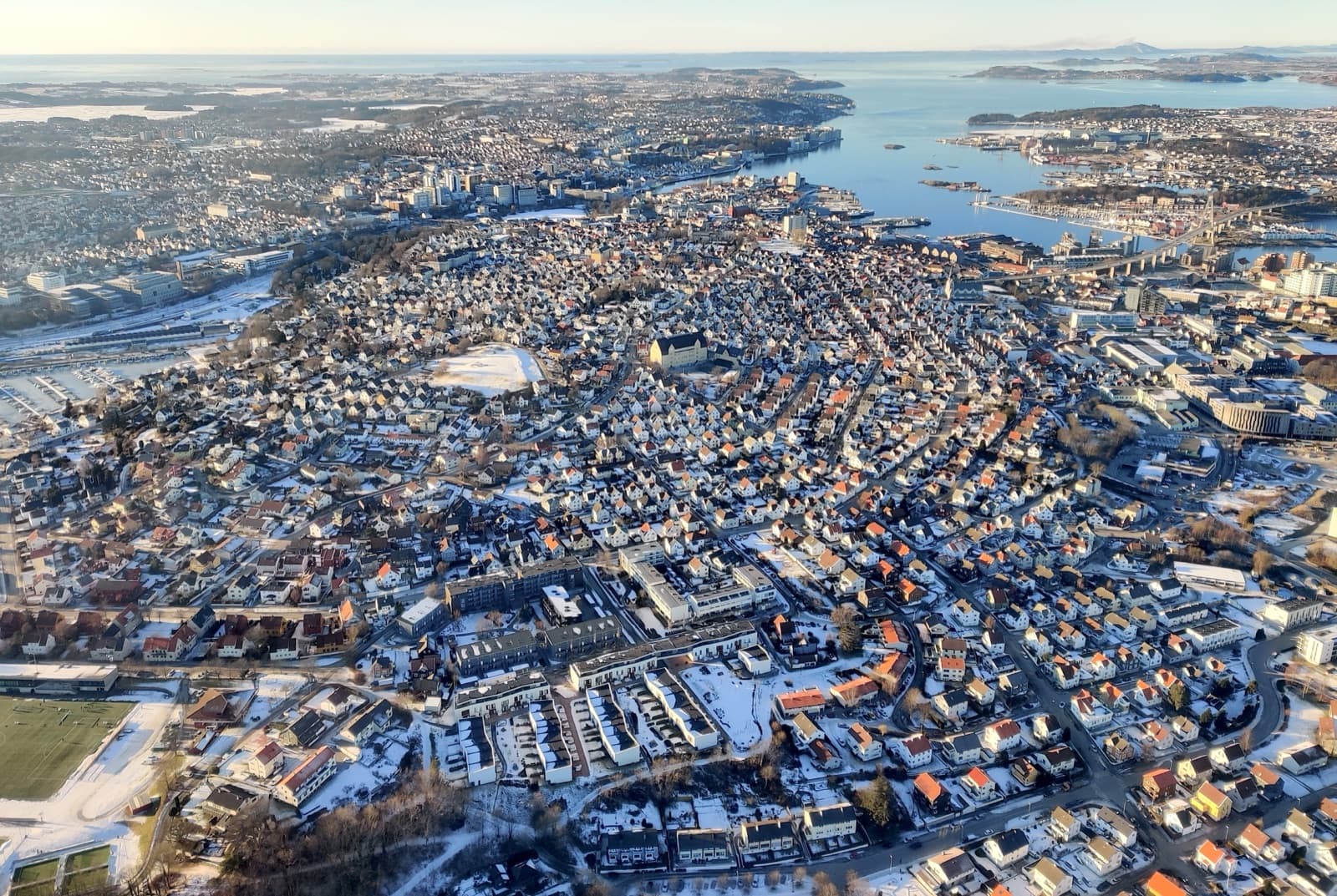Winter aerial view over the dense wooden housing of Storhaug with the harbour and the fjord beyond, Stavanger, Norway.