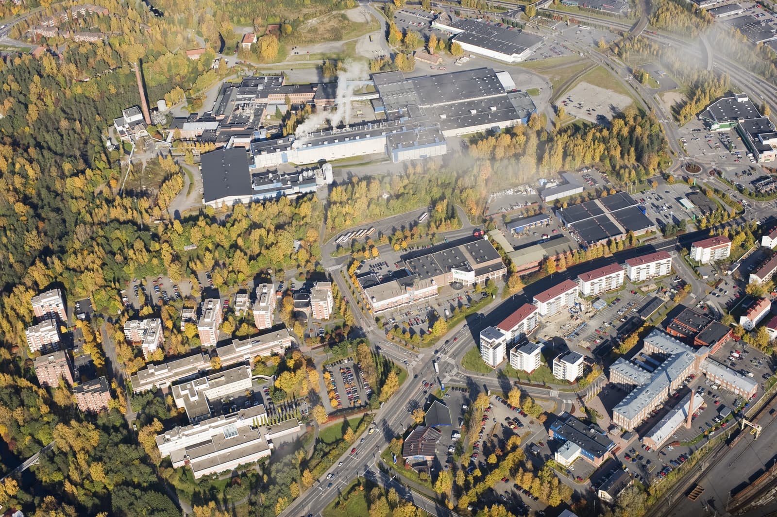 Tourula in Jyväskylä from the air in autumn colours, the old mill buildings and the district's blocks set between wooded slopes.