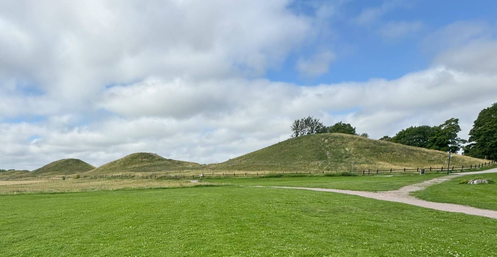 The three Royal Mounds (Kungshögarna) rising from open meadow at Gamla Uppsala, Uppsala, Sweden.