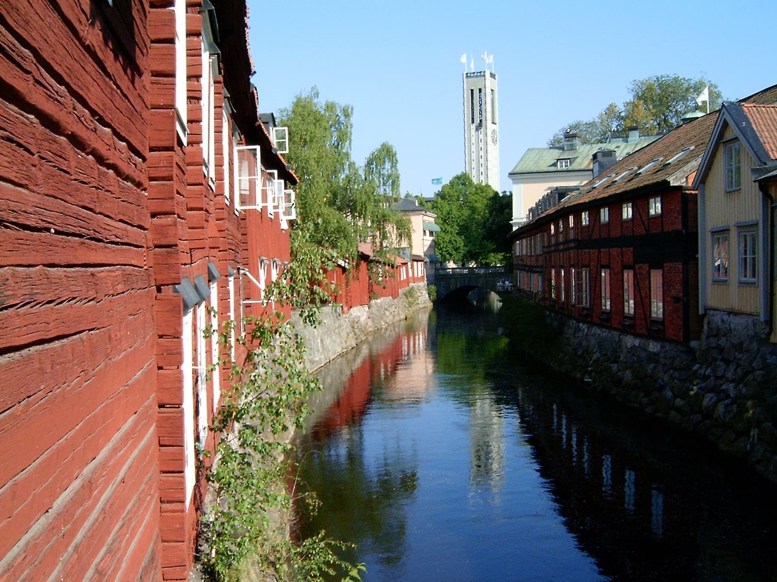 The Svartån river running through central Västerås, Sweden, seen from Apotekarbron with timber buildings along the banks and the town hall tower beyond.