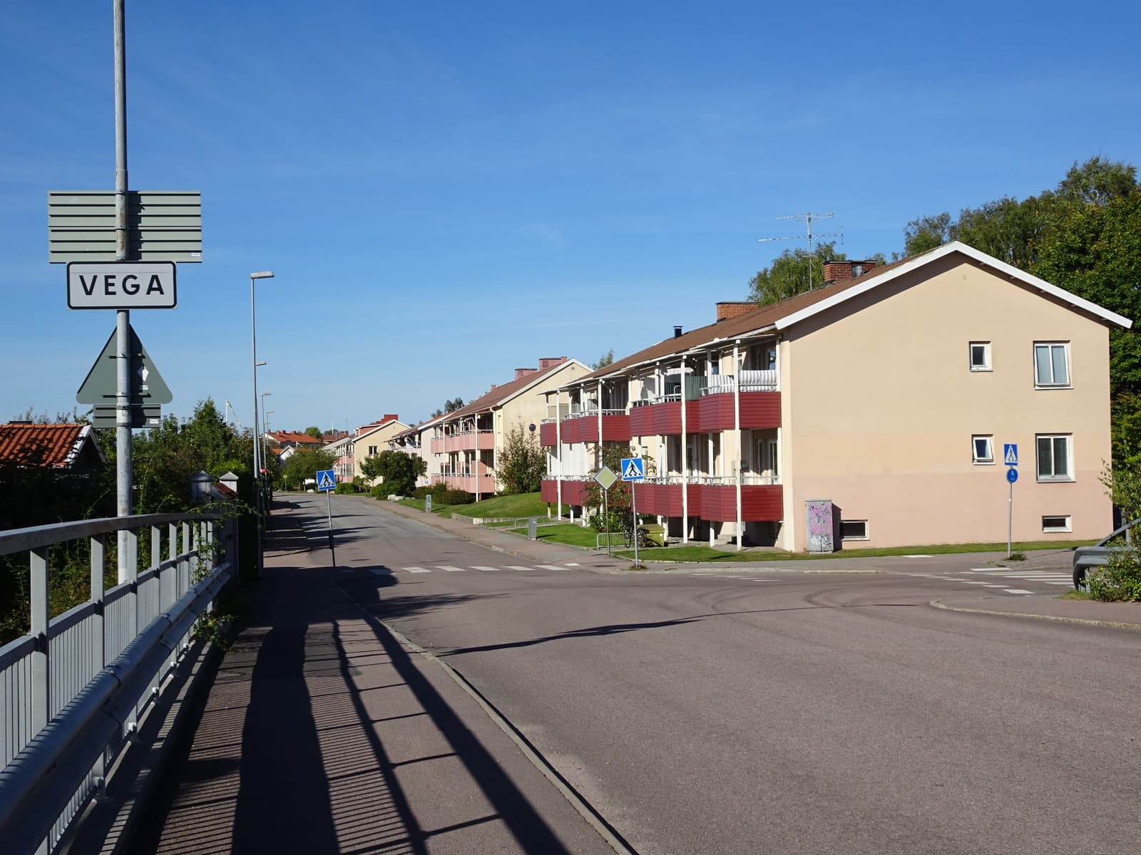 A quiet residential street (Tunbyvägen) in the Vega district of Västerås, Sweden, lined with houses and greenery.