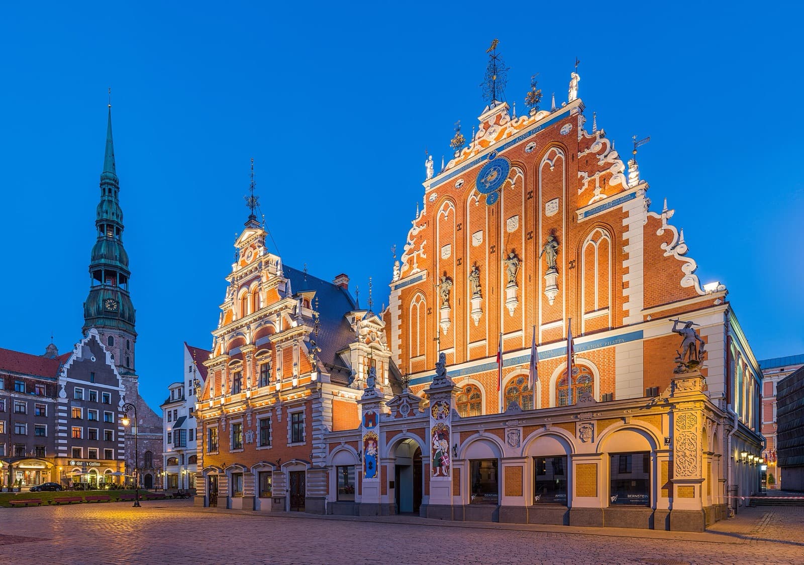 The House of Blackheads and St. Peter's Church tower above the cobbled Town Hall Square at dusk in Rīga Old Town.