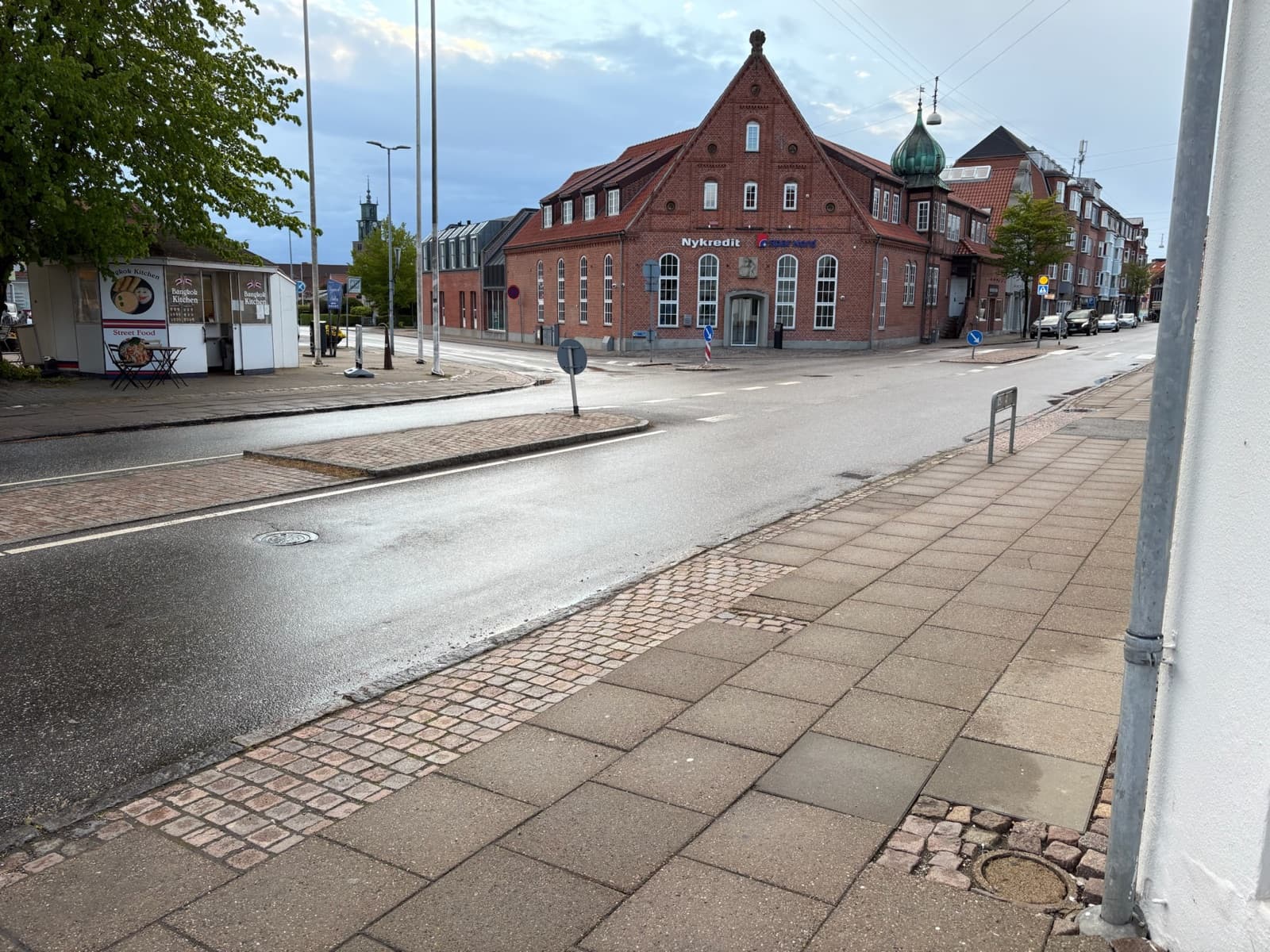 The centre of Vejgaard in eastern Aalborg, with a red-brick landmark building topped by a green onion-dome tower on the main shopping street, Denmark.
