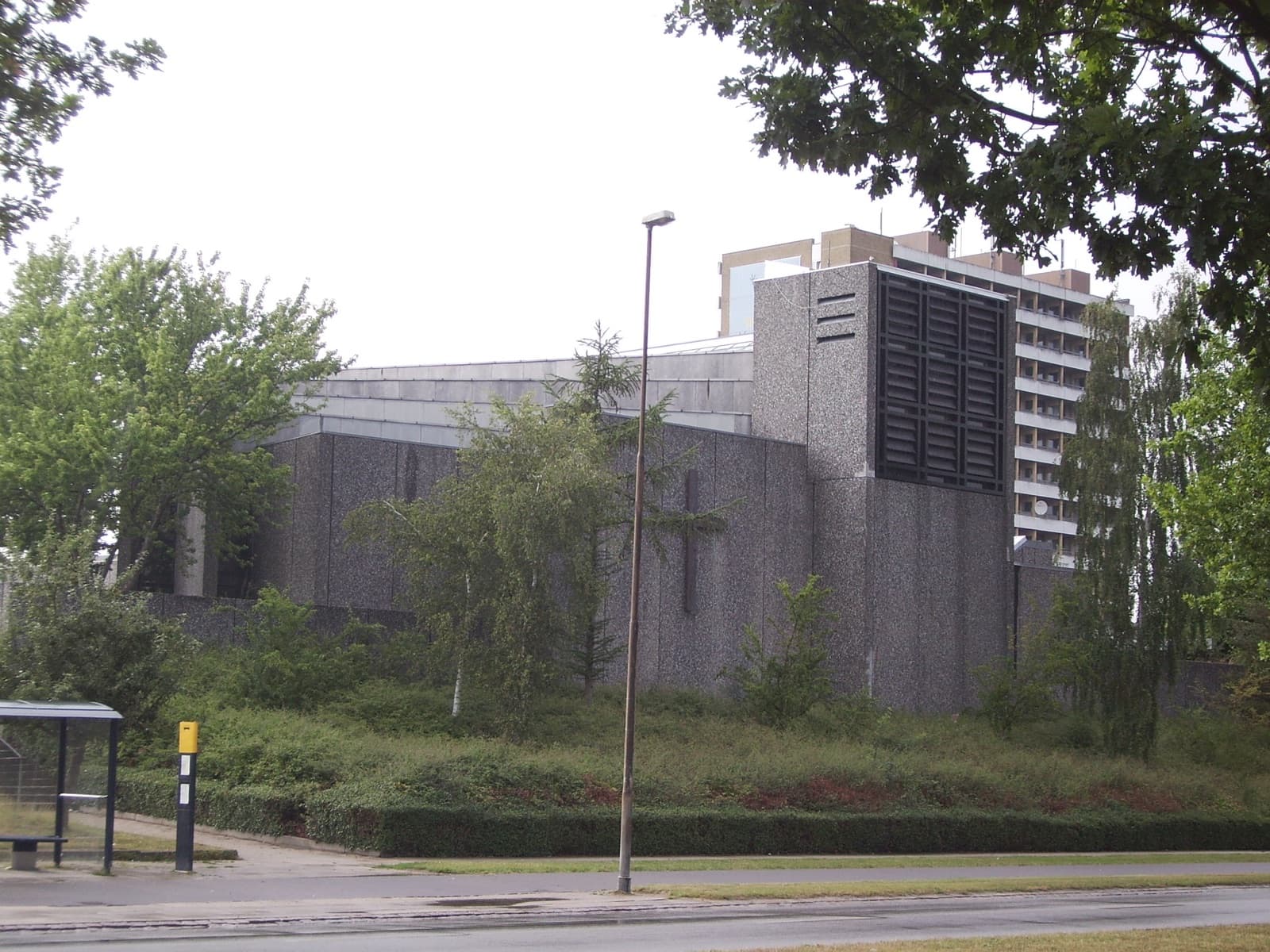 The modern concrete Vollsmose Church with a pale high-rise apartment tower behind it in the Vollsmose estate, north-east Odense.