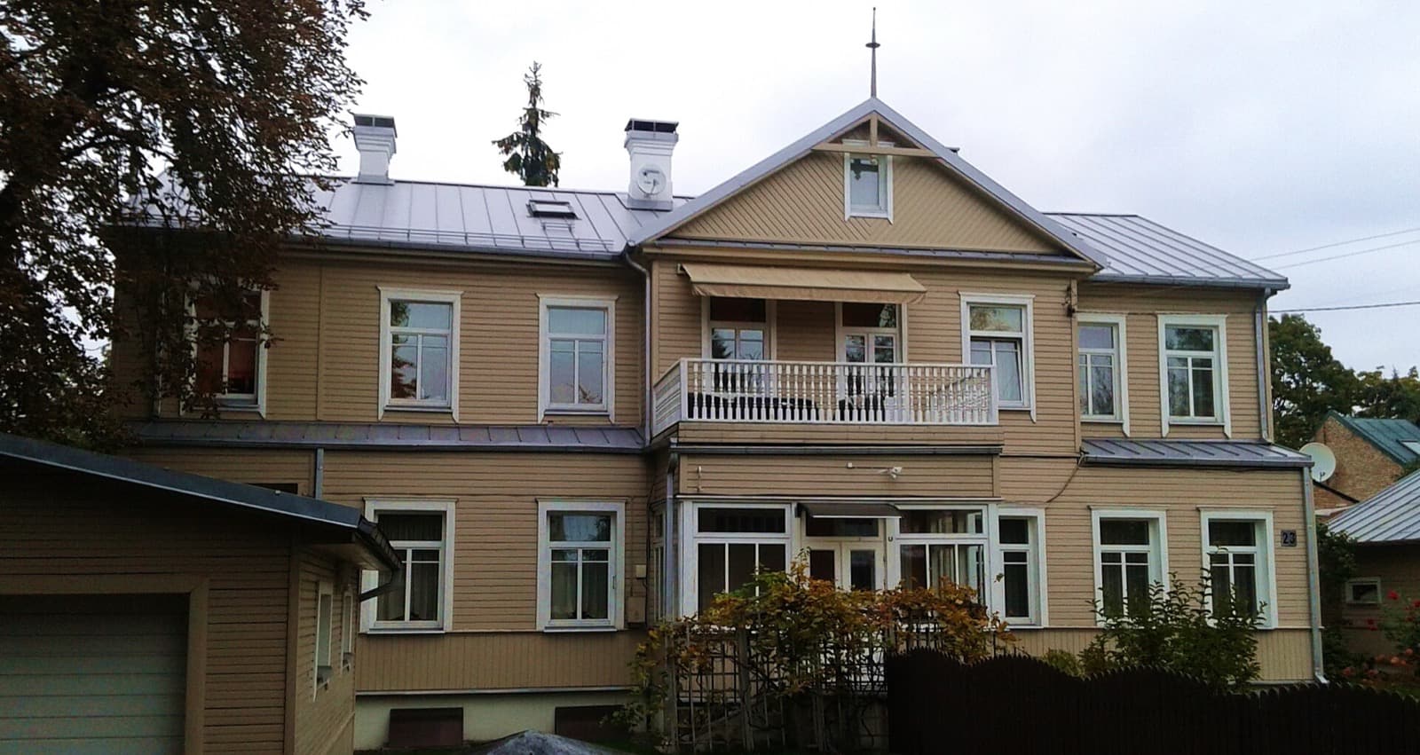 A traditional two-storey wooden villa with a carved balcony, typical of the leafy streets of Zverynas.