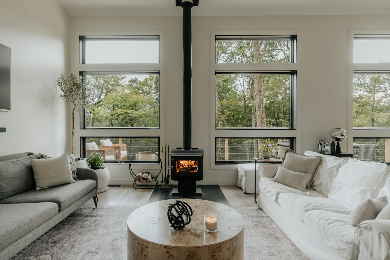 A bright, well-kept living room with a wood stove and large windows