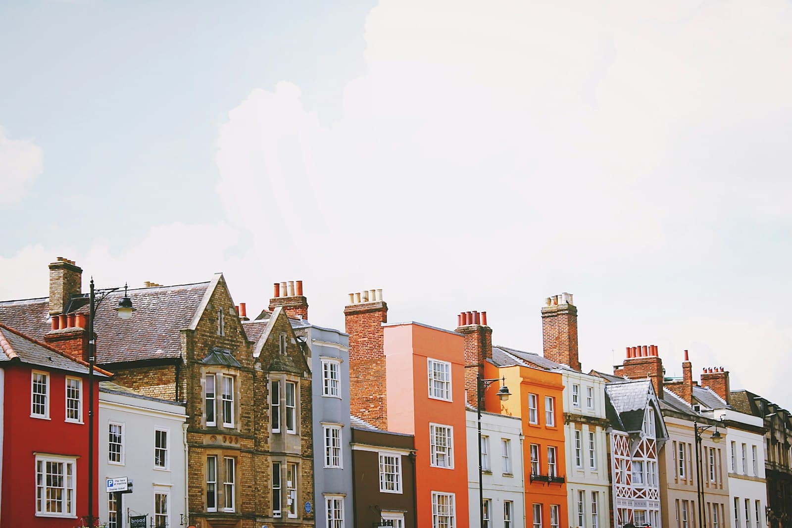 A colourful row of terraced townhouses with brick chimneys under a bright sky