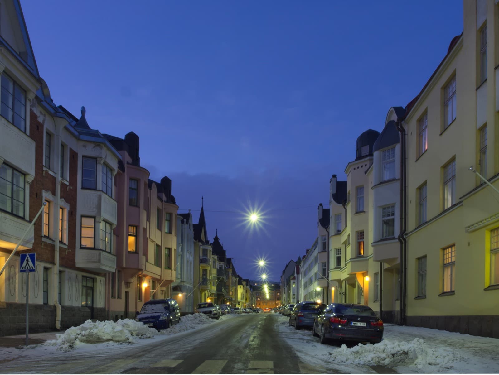 Pastel Jugend facades lining Huvilakatu in the Eira quarter of Ullanlinna, Helsinki, at blue hour on a snowy winter evening.